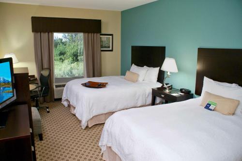 a hotel room with two beds and a flat screen tv at Hampton Inn Orange in Orange