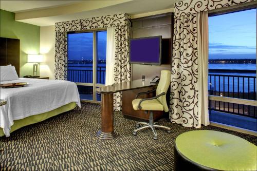 a hotel room with a bed and a desk and windows at Hampton Inn & Suites Baton Rouge Downtown in Baton Rouge