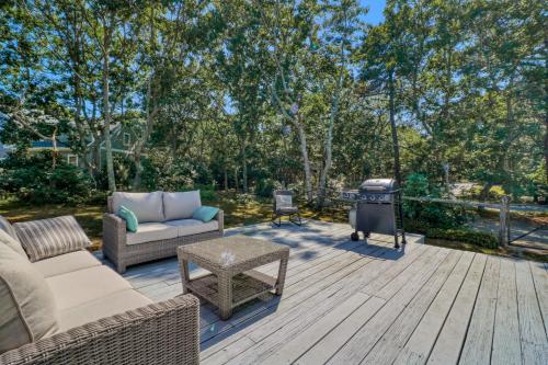 a patio with a couch and a grill and trees at Martha's Hideaway in Edgartown