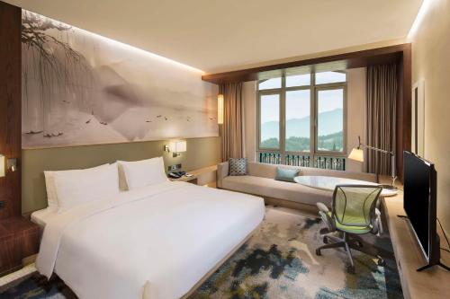 een slaapkamer met een groot wit bed en een televisie bij Hilton Garden Inn Hangzhou Lu'Niao in Anji