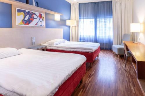 um quarto de hotel com duas camas e uma secretária em Scandic Atrium em Turku