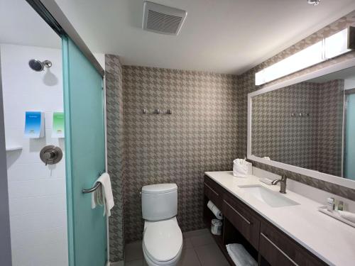 a bathroom with a toilet and a sink and a mirror at Home2 Suites By Hilton Atlanta Camp Creek Parkway, Ga in Atlanta