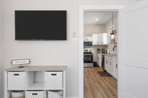 a kitchen with white cabinets and a flat screen tv at Cowboy Pool 2 mins 2 Silos & Cameron Park in Waco