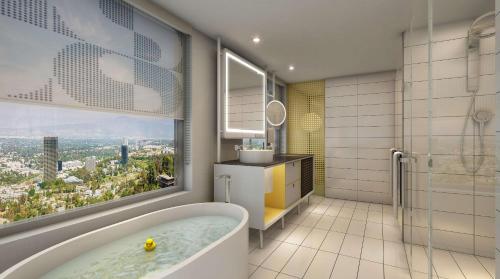 a bathroom with a bath tub and a window at Hilton Buena Park in Buena Park