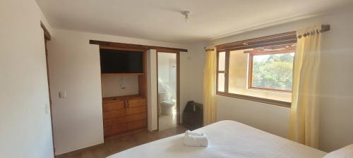 a bedroom with a bed and a window and a television at Hotel Villa Javier VDL in Villa de Leyva