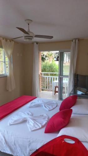 1 dormitorio con 1 cama grande con almohadas rojas en Pousada Rota Do Beija Flor PACOTI-CE en Pacoti