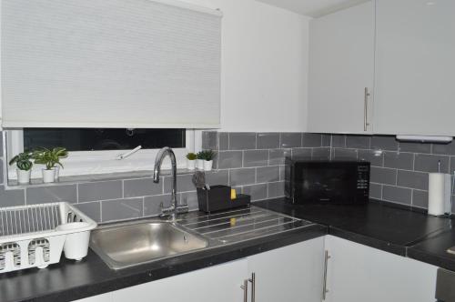 a kitchen with white cabinets and a sink at Flat very close to Stratford! in London