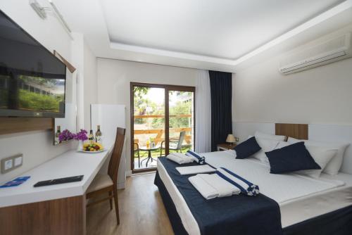 a bedroom with a bed and a desk and a television at Amore Hotel Teki̇rova in Tekirova