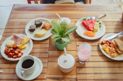einen Holztisch mit Teller mit Speisen und Getränken in der Unterkunft Pousada Paraíso do Vento in Cumbuco