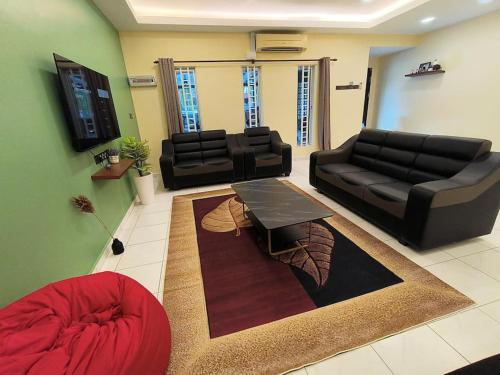 a living room with a black couch and a table at (WI-FI) Ipoh Holiday Big House double storey DR8 in Ipoh