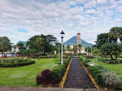 a walkway through a park with a clock tower at La Fortuna Lodge by Treebu Hotels in Fortuna