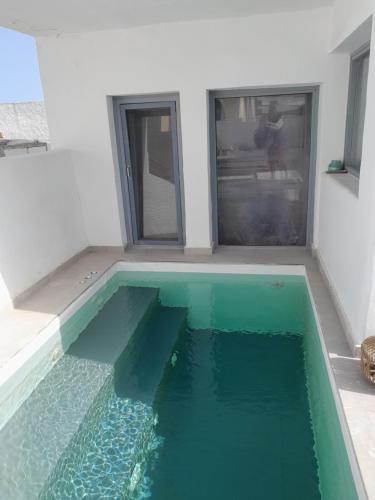 a swimming pool with green water in a room at SPILIOTICA VILLAS AND APARTMENTS in Imerovigli