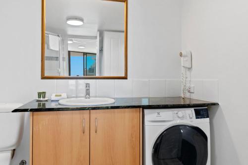 a bathroom with a sink and a washing machine at Top Floor Beachside Apartment in the Heart of Mooloolaba in Mooloolaba