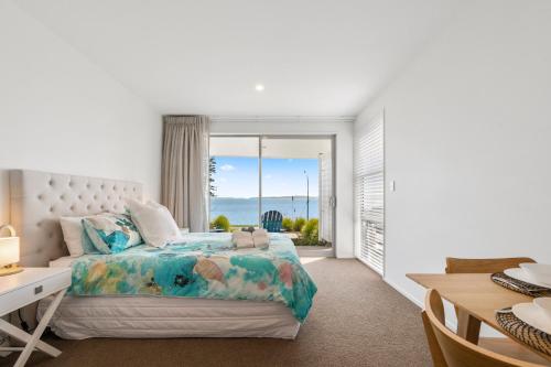 a bedroom with a bed with a view of the ocean at Maraetai Couples Retreat - Omana Beach Apartment in Auckland