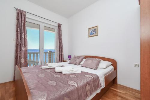 a bedroom with a bed with a large window at Apartments by the sea Pisak, Omis - 10323 in Pisak