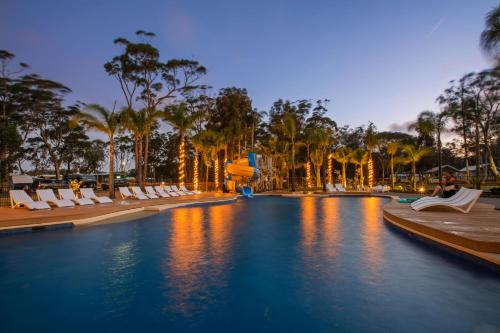 a pool at a resort with lounge chairs and palm trees at BIG4 Tasman Holiday Parks - Racecourse Beach in Bawley Point