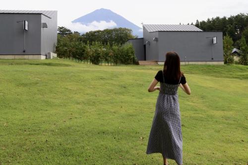 a woman standing in a field looking at a mountain at グランピングヴィレッジ富士河口湖 in Narusawa
