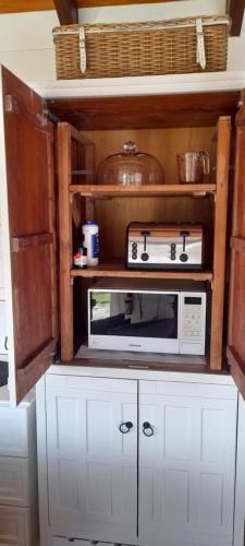 a kitchen with a microwave and some pots and pans at Wharfe Cottage in Wellsford