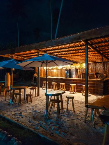 a group of tables and chairs with umbrellas at night at Taboo Milagres in São Miguel dos Milagres