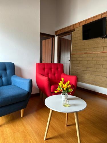 uma sala de estar com duas cadeiras e uma mesa com flores em Hotel Villa Teresita em Sáchica