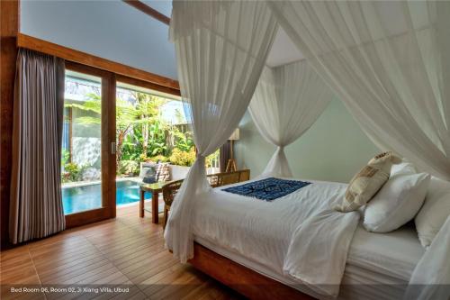 um quarto com uma cama com cortinas brancas e uma piscina em Jixiang Hotel Ubud em Ubud