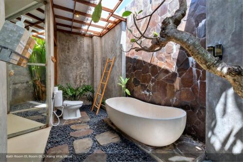 uma banheira na casa de banho com uma parede de pedra em Jixiang Hotel Ubud em Ubud