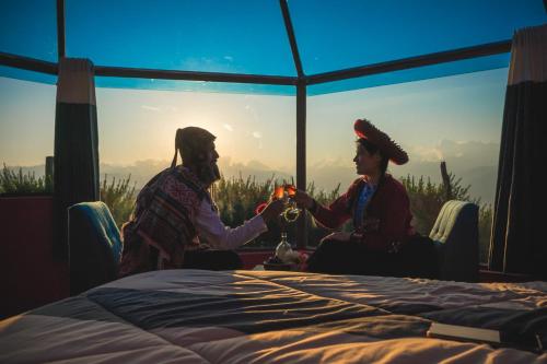 a man and woman sitting next to a bed at Sky Dome Peru in Cusco