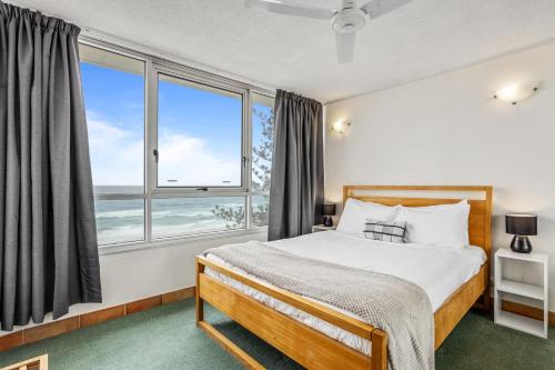 ein Schlafzimmer mit einem Bett und einem großen Fenster in der Unterkunft Impressive Waterfront at Chateau Beachside Resort in Gold Coast