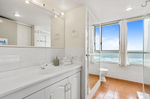 ein weißes Bad mit einer Dusche und einem Fenster in der Unterkunft Impressive Waterfront at Chateau Beachside Resort in Gold Coast
