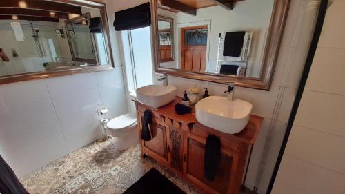 a bathroom with two sinks and a toilet and a mirror at Wharfe Cottage in Wellsford