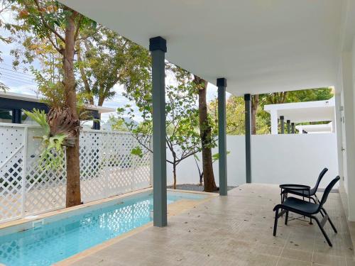 a patio with two chairs next to a swimming pool at สายลม รีสอร์ท เขาใหญ่ in Pak Chong