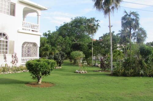 a yard in front of a white house with trees at Nelsons Retreat in Negril