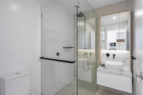 a white bathroom with a sink and a shower at Wave Watcher's Delight at Acqua Palm Beach in Gold Coast