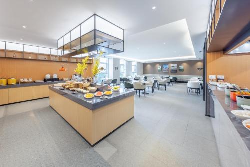 een grote keuken en eetkamer met tafels en stoelen bij Atour X Hotel Shanghai Shuguang Wusong Cruise Terminal 