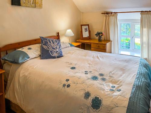 um quarto com uma cama grande e almofadas azuis em Fedwr Gog Cottage em Llangwm