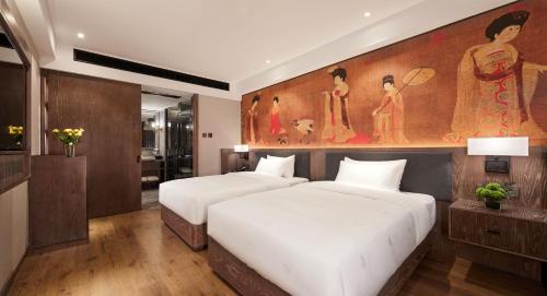 two beds in a room with a painting on the wall at Yiwu Manxin Hotel in Yiwu