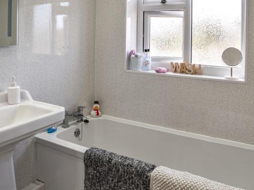 a bathroom with a tub and a sink and a window at Wylandre in Amlwch
