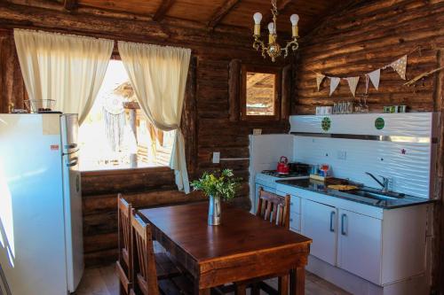 cocina con mesa y nevera en INCA ROCA Cabañas de Montaña en Uspallata