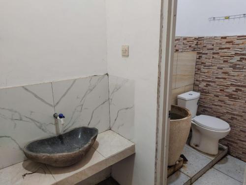 a bathroom with a stone sink and a toilet at Mulia Homestay Pasuruan 