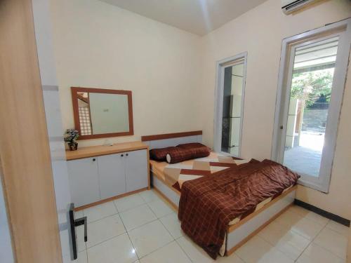 1 dormitorio con 2 camas, espejo y ventana en Mulia Homestay Syariah Pasuruan 