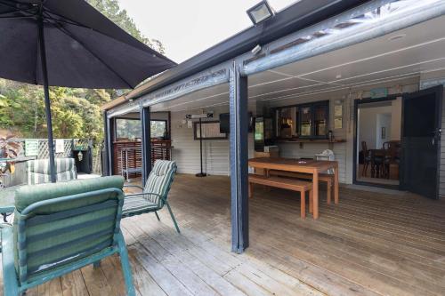 een terras met een tafel en stoelen en een parasol bij Tui Lodge Oakura 