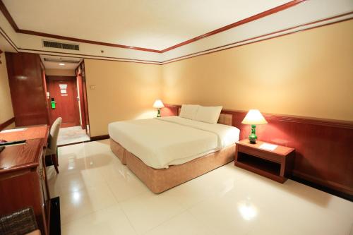 a bedroom with a bed and a table with a lamp at Kosa Hotel & Wellness Center -SHA Certified in Khon Kaen