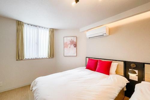Un dormitorio con una cama con dos almohadas rojas. en SEED Tanimachi 6-chome, en Osaka