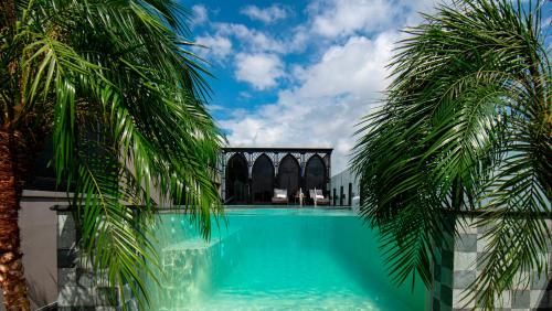 a pool with turquoise water between two palm trees at Le Chanvre Hanoi Hotel & Spa in Hanoi