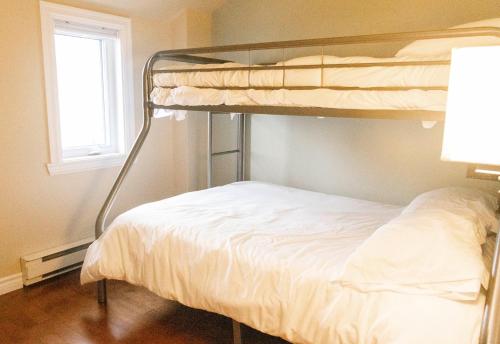 ein Schlafzimmer mit Etagenbett und Fenster in der Unterkunft Les Condos de la Montagne 2 in Beaupré