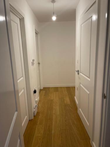 an empty hallway with white walls and wooden floors at Amazing Luxury Double Bedroom with en-suite shower and free parking with a Sound bar & smart TV in a two bed Apartment I live in the 2nd room in Belvedere