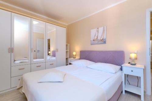 a bedroom with a large white bed with a purple headboard at Apartments with a parking space Mali Losinj (Losinj) - 15201 in Mali Lošinj