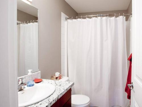 a bathroom with a sink and a white shower curtain at Breakaway Beach Villa near Lake in Penticton