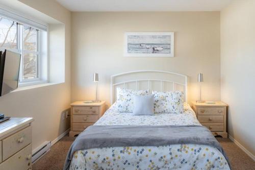 a bedroom with a bed with two night stands and two lamps at Breezy Beach Villa near the Lake in Penticton