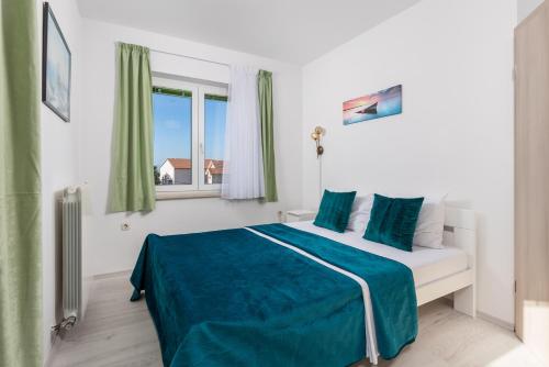 - une chambre avec un lit doté de draps bleus et une fenêtre dans l'établissement Apartment Kraljevica 17589b, à Kraljevica